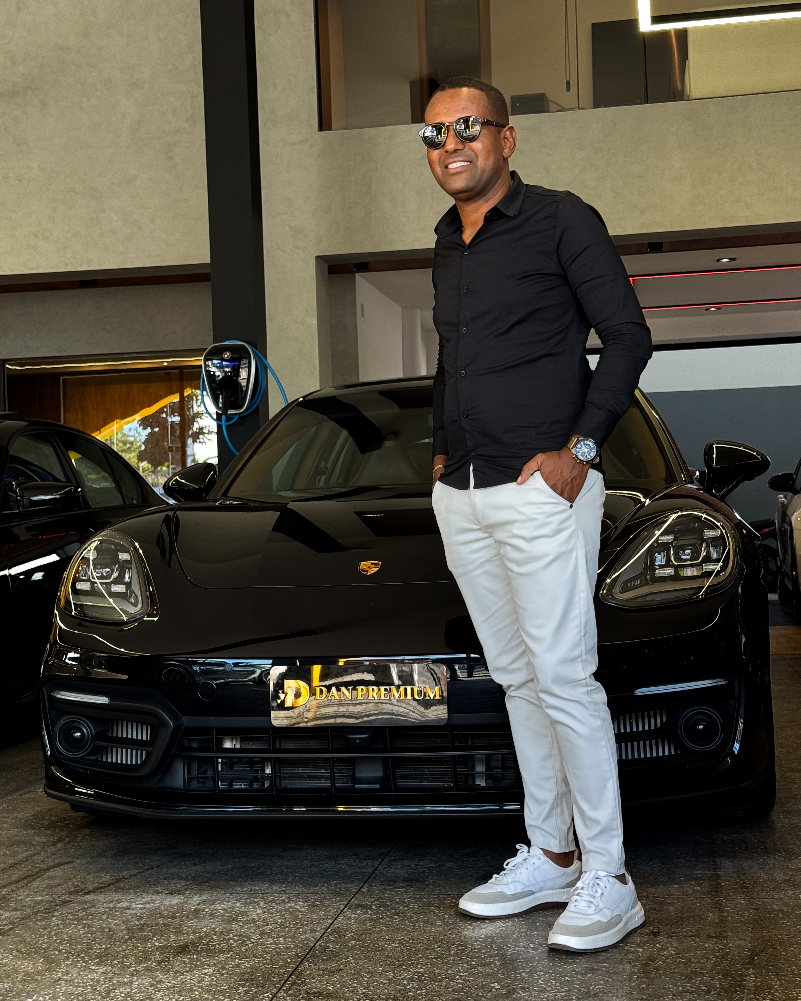 Dan, fundador da Dan Premium, em frente a um Porsche Panamera preto